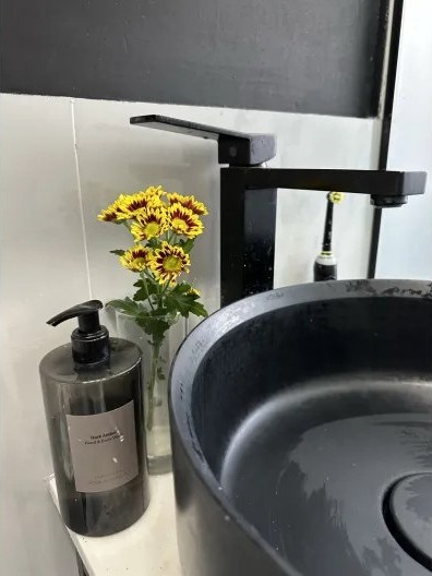 Black stone vessel sink with fresh flowers